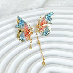 Handmade Pink Blue Butterflies with Drops Earrings These lightweight handmade earrings feature an intricate pink and blue butterfly wing design accented by a drop design. Perfect for a special occasion or everyday wear. As a gift shop, we offer a complimentary gift box for every order. Some details - Size of earring: around 20mm*30mm Materials: Ear stud: gold-plated sterling silver The base of earring: resin The Handmade Pink Blue Butterflies with Drops Earrings are sold on pair of two earrings. About postage: Standard postage When choosing standard postage, we assume this order is for yourself, or you will wrap the item yourself before giving it out as a gift (the complimentary gift box would be posted flat with your order under standard postage). Hence, to be environmentally friendly and Pink And Blue Butterfly, Butterfly Wing Design, Blue Butterfly Wings, Wing Design, Unique Handmade Earrings, Butterfly Wing Earrings, Headpiece Jewelry, Blue Butterflies, Bleu Violet