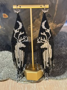 two black and white beaded earrings on a stand