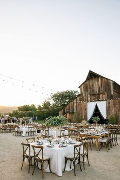 a barn with tables and chairs set up for an outdoor wedding