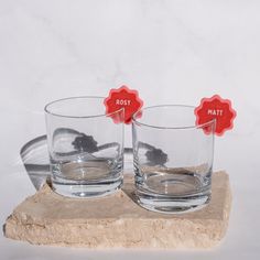 two glasses sitting on top of a rock next to each other