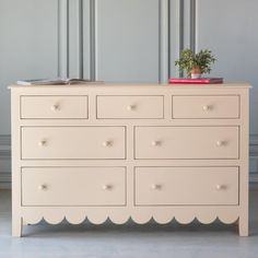 a white dresser with two books and a potted plant on top