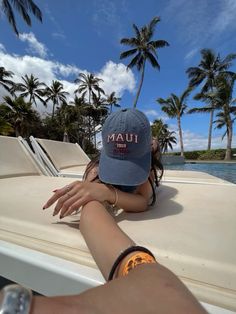 a woman laying on the back of a boat with palm trees in the background