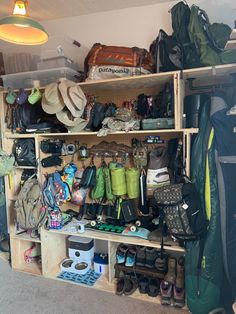 a room filled with lots of different types of bags and hats on shelves next to a lamp