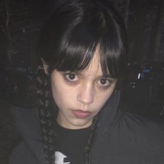 a girl with black hair and braids looks at the camera while wearing a jacket