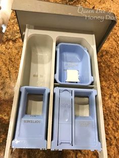 three empty blue containers in a box on a counter top, with the lids open