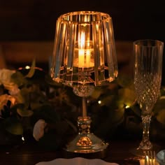 a lit candle sitting on top of a table next to a wine glass and silverware