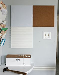 a white box sitting on top of a table next to a corkboard wall hanging