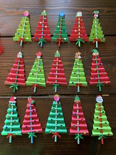 christmas trees made out of construction paper are displayed on a wooden table with other decorations