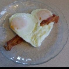 an egg and bacon breakfast on a clear glass plate