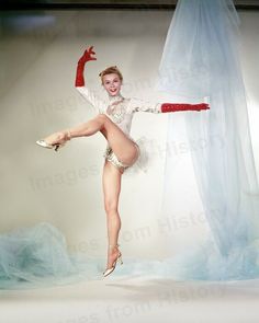 a woman in a white leotard and red stockings is posing for a photo