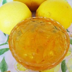 three lemons and two oranges on a floral tablecloth with a glass bowl