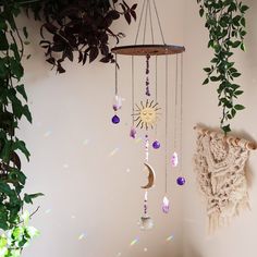 a sun and moon mobile hanging on the wall next to a tree with purple crystals