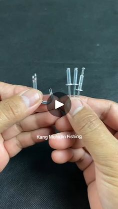 two hands are holding tiny pins in their fingers