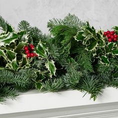 a white mantle with holly and red berries on it