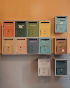 several mail boxes mounted to the side of a wall next to each other in different colors