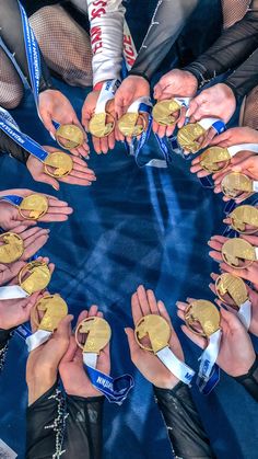 a group of people standing around each other holding up gold medals in front of them