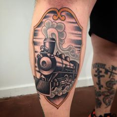 a man's leg with an old school train tattoo on it and his legs