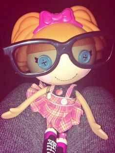 a doll with glasses sitting on top of a couch