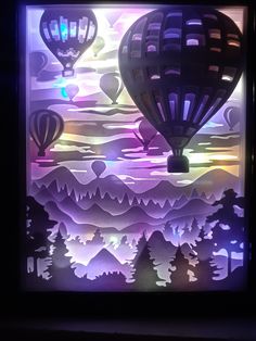 some hot air balloons are flying in the sky above trees and mountains at night time