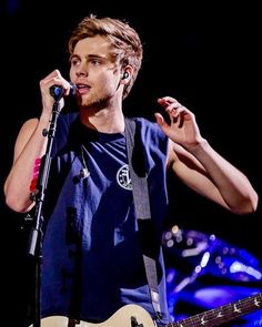 a young man holding a microphone up to his ear