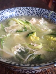 a blue and white bowl filled with soup on top of a wooden table