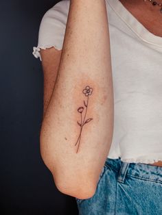 a woman's arm with a flower tattoo on the left side of her arm