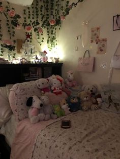 a bed with many stuffed animals on top of it and flowers hanging from the ceiling