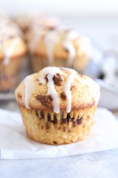 a muffin with icing sitting on top of a piece of paper next to other muffins