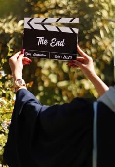 a woman holding up a clapper in front of her face with the end written on it