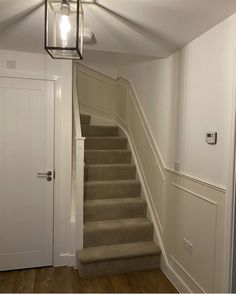 a light that is on above a set of stairs in a room with white walls