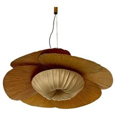 an unusual light fixture made out of wood and fabric, hanging from a ceiling fan