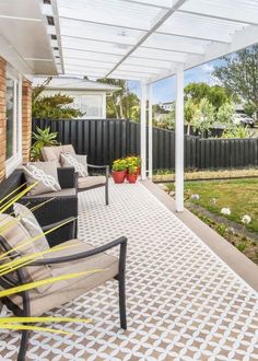 a covered patio with chairs and potted plants on the side walk next to it