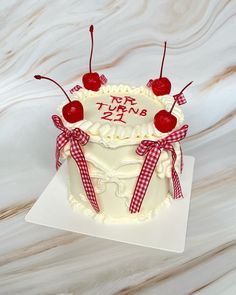 a white cake with cherries on top and the words happy birthday written on it