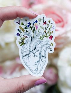 a hand holding up a sticker with an elephant and flowers on it's back