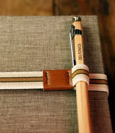 a wooden pen sitting on top of a book with a leather strap around it's end