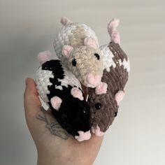 a hand holding three small crocheted animals in it's palm, one is brown and the other is white