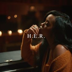 a woman sitting in front of a piano with her hand on her mouth and the words h e r