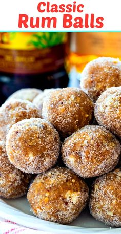 a white plate topped with sugar covered donuts next to a jar of rum syrup