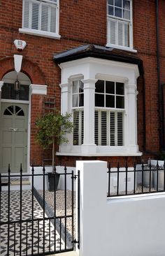 a brick building with white windows and black iron fence