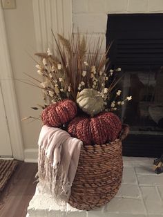 a basket filled with balls of yarn sitting on top of a floor next to a fire place