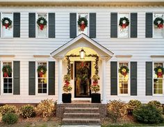 a white house decorated for christmas with wreaths and lights