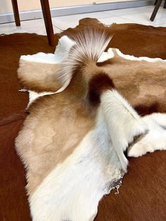 a brown and white animal skin laying on top of a floor next to a chair