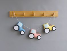 three toy cars are hanging on a clothes line with pegs attached to the hooks