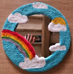 a handmade mirror with clouds, rainbows and a person taking a photo in the mirror