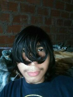 a young man with black hair and bangs on his head, wearing a t - shirt