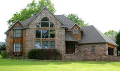 a large brick house sitting on top of a lush green field