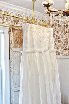 a white dress hanging on a clothes line in front of a wallpapered room