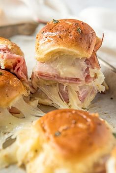 two ham and cheese sliders sitting on top of a plate next to some bread