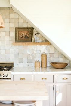 a kitchen with a stove top oven under a slanted ceiling next to a wooden table