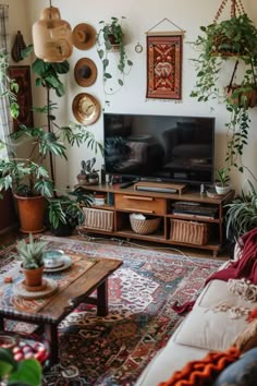 a living room filled with lots of plants next to a flat screen tv on top of a wooden stand